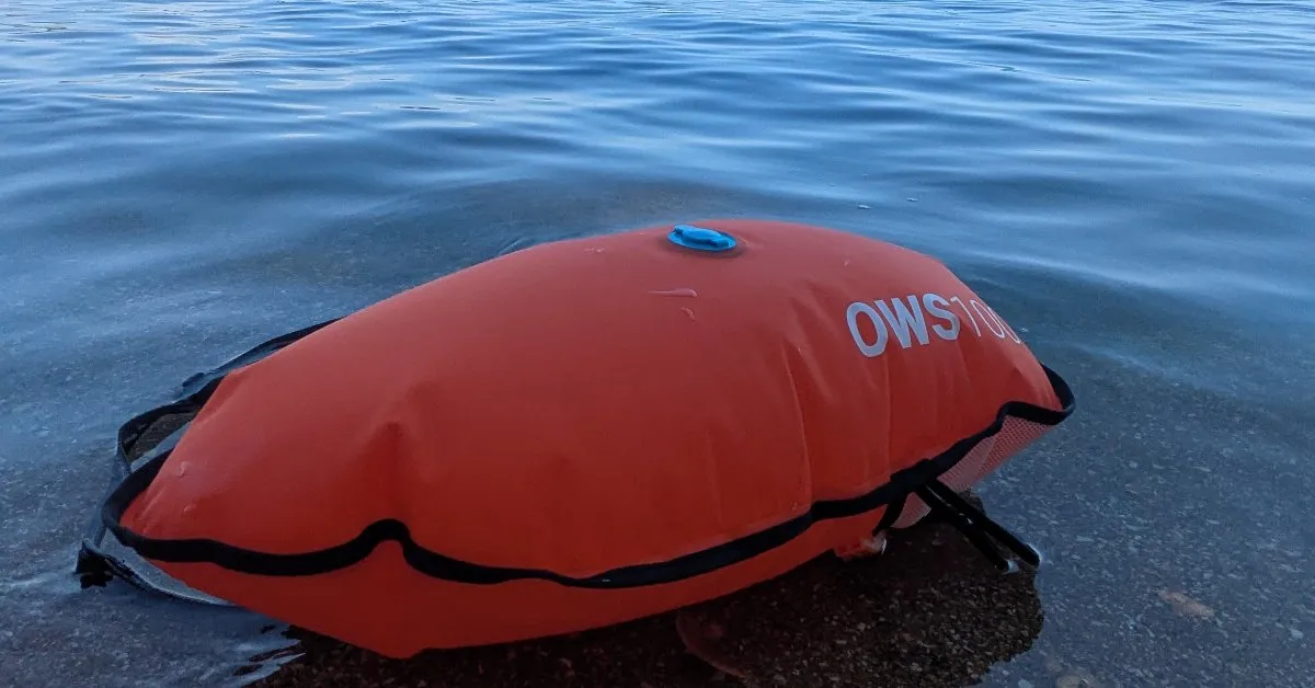 Bouée de nage en eau libre OWS 100 orange gonflée, posée au bord de l'eau avant une séance de natation