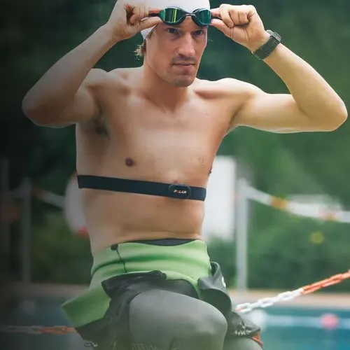 Nageur en combinaison ajustant ses lunettes de natation avec la ceinture Polar H10 sur le torse avant un départ en eau libre