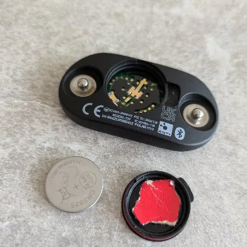 Compartiment pile ouvert du Polar H10 avec une CR2025 posée à côté avant le fix papier