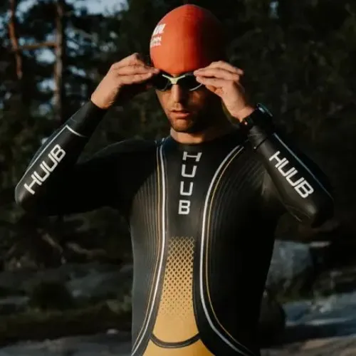 Triathlète en combinaison HUUB ajustant ses lunettes avant un départ en eau libre, montre Polar au poignet