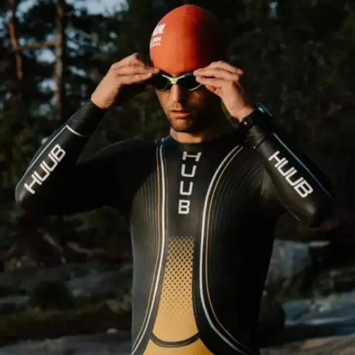 Triathlète en combinaison HUUB ajustant ses lunettes avant un départ en eau libre, montre Polar au poignet